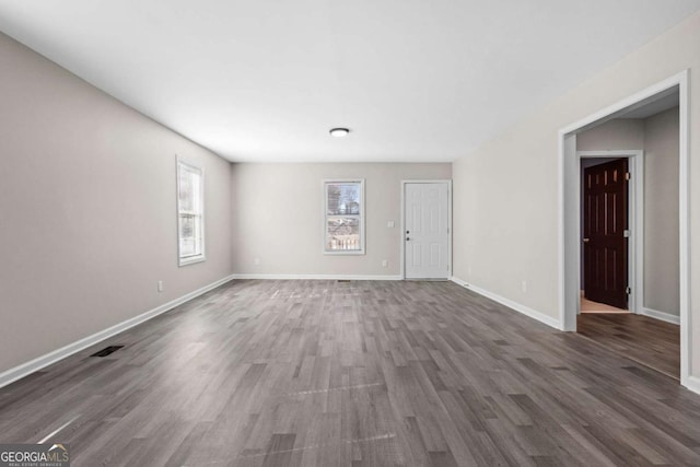 unfurnished living room featuring baseboards, wood finished floors, and visible vents