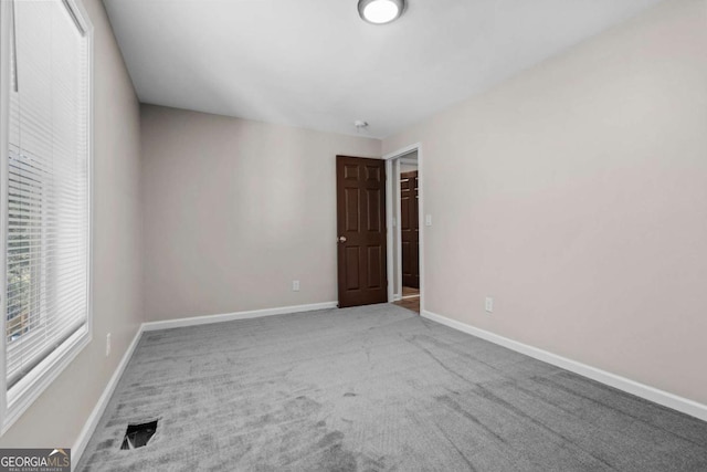spare room with baseboards, visible vents, and carpet