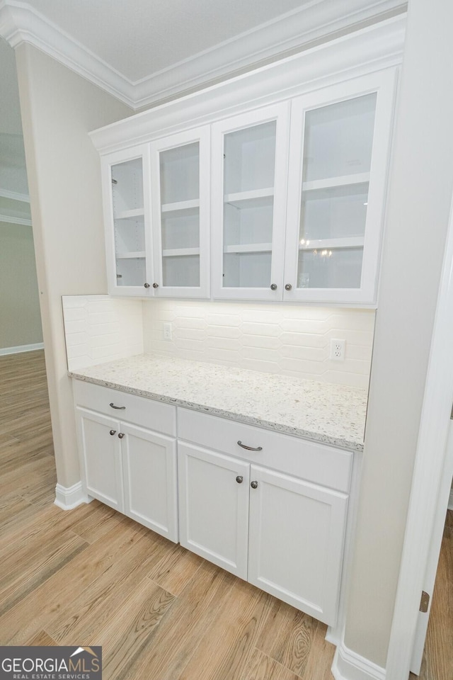 bar featuring light wood-style floors, ornamental molding, baseboards, and tasteful backsplash