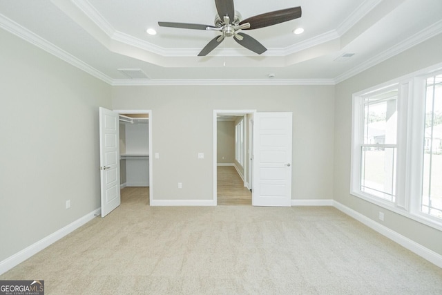 unfurnished bedroom featuring a tray ceiling, ornamental molding, and light carpet