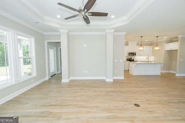 unfurnished living room featuring visible vents, baseboards, ceiling fan, light wood-type flooring, and a sink