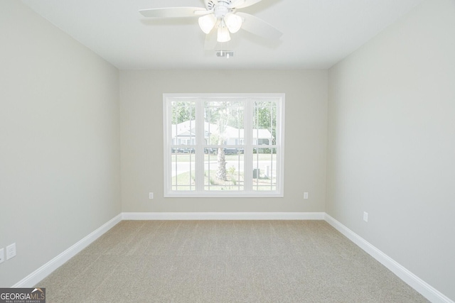 empty room with baseboards, ceiling fan, light carpet, and visible vents
