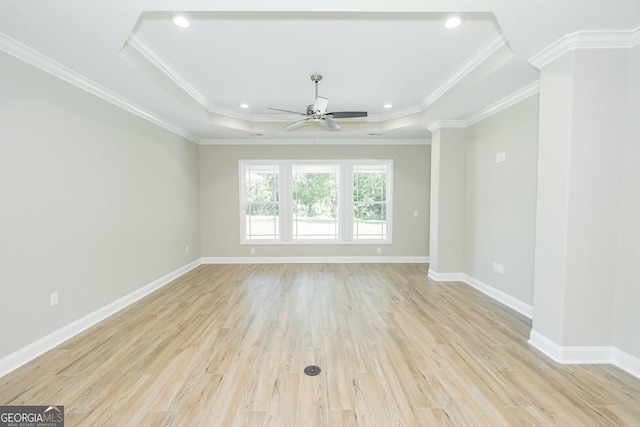 spare room featuring ceiling fan, light wood-type flooring, baseboards, a raised ceiling, and ornamental molding