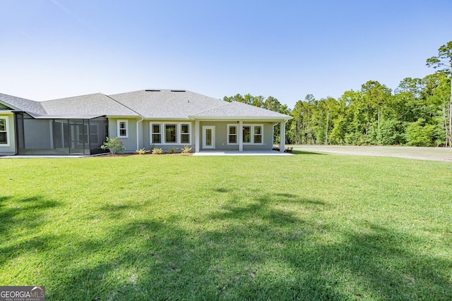 back of house with a shingled roof, a yard, and a patio area