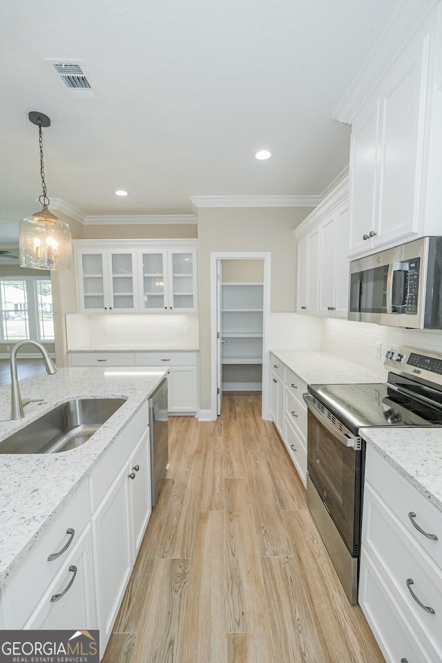 kitchen featuring crown molding, white cabinets, a sink, stainless steel appliances, and visible vents