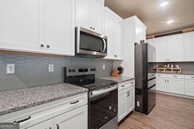 kitchen featuring light wood-style floors, white cabinetry, light stone counters, backsplash, and stainless steel appliances