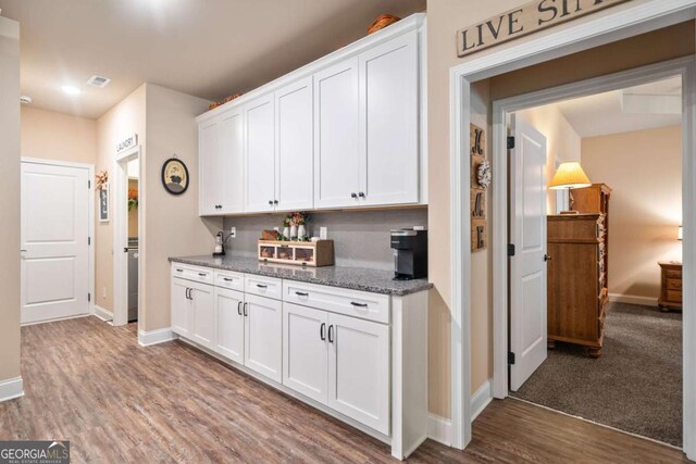 kitchen with white cabinets, baseboards, stone counters, wood finished floors, and visible vents