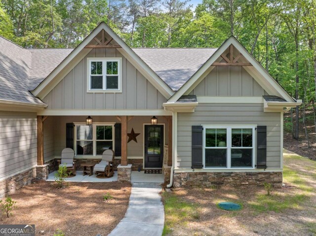 craftsman inspired home with board and batten siding, stone siding, and roof with shingles