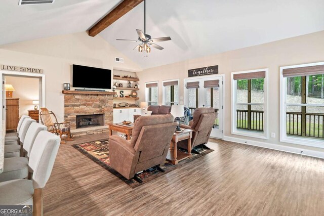 living area featuring ceiling fan, a stone fireplace, visible vents, wood finished floors, and vaulted ceiling with beams