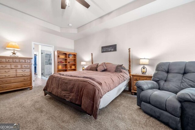 carpeted bedroom featuring a ceiling fan and ensuite bath