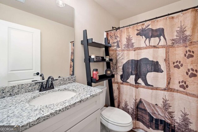 full bath with vanity, a shower with shower curtain, and toilet