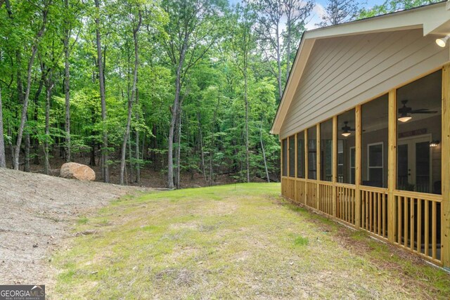 view of yard featuring ceiling fan and a sunroom