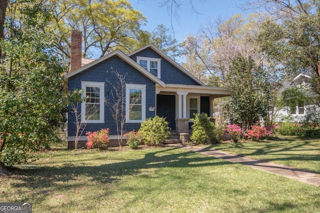 view of front of house with a porch, a chimney, and a front yard