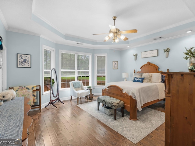bedroom featuring a tray ceiling, ornamental molding, and wood finished floors