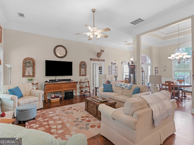 living area featuring crown molding, ceiling fan with notable chandelier, visible vents, and wood finished floors