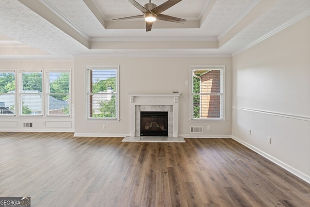 unfurnished living room featuring plenty of natural light, a raised ceiling, wood finished floors, and visible vents