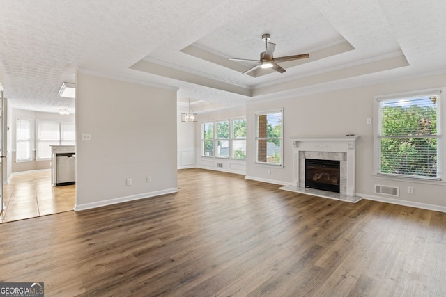 unfurnished living room featuring visible vents, a high end fireplace, ceiling fan with notable chandelier, and a wealth of natural light
