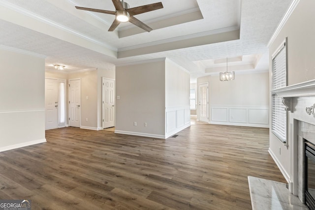 unfurnished living room featuring crown molding, a high end fireplace, a raised ceiling, and ceiling fan with notable chandelier