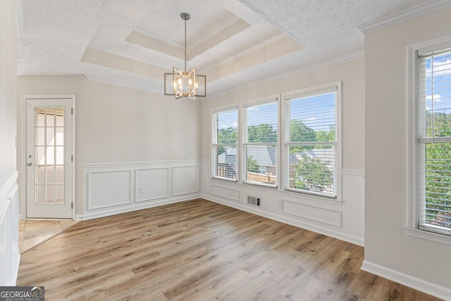 unfurnished dining area featuring visible vents, wainscoting, a decorative wall, wood finished floors, and a notable chandelier
