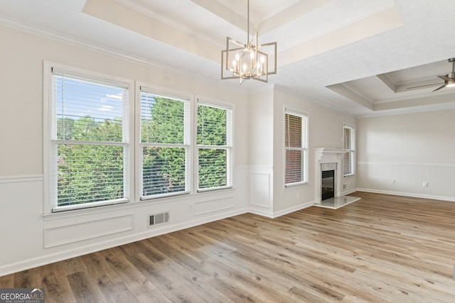 unfurnished living room featuring visible vents, ornamental molding, a raised ceiling, and a wealth of natural light