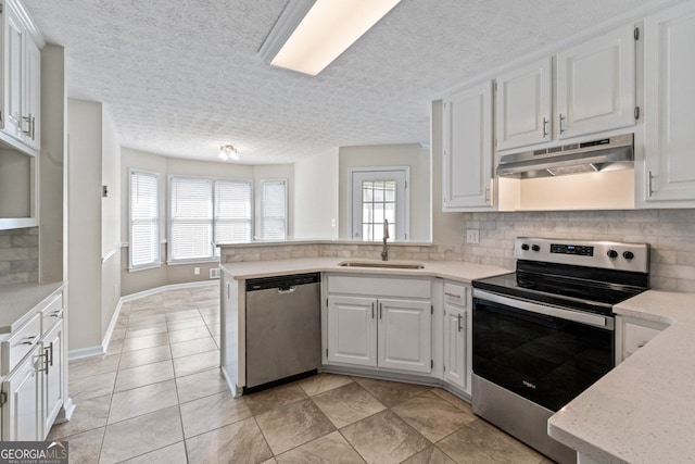 kitchen with decorative backsplash, a textured ceiling, appliances with stainless steel finishes, a sink, and under cabinet range hood