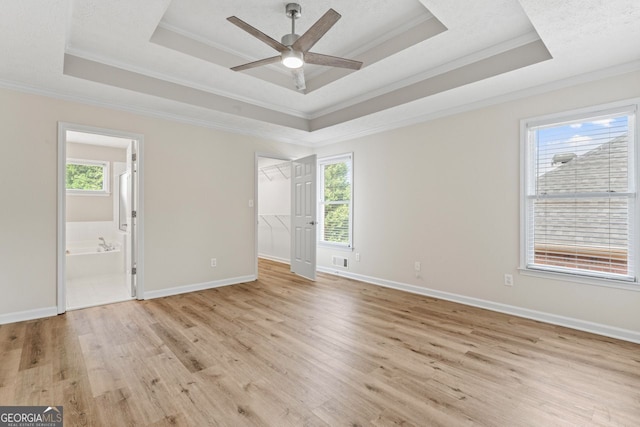 empty room with crown molding, a raised ceiling, and a wealth of natural light