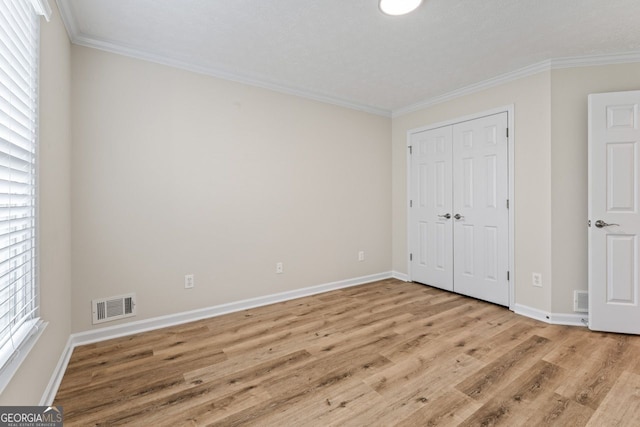 unfurnished bedroom featuring visible vents, baseboards, crown molding, and wood finished floors