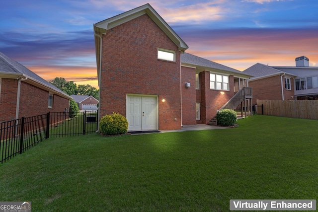 rear view of property featuring a fenced backyard, stairs, a yard, and brick siding