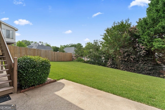 view of yard with a patio, a fenced backyard, and stairs