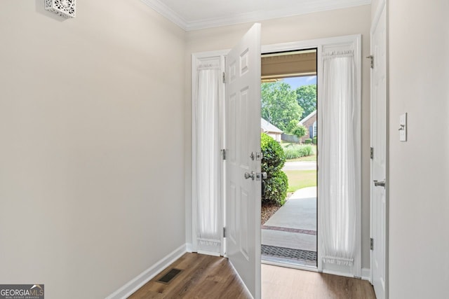 entryway with crown molding, baseboards, wood finished floors, and visible vents