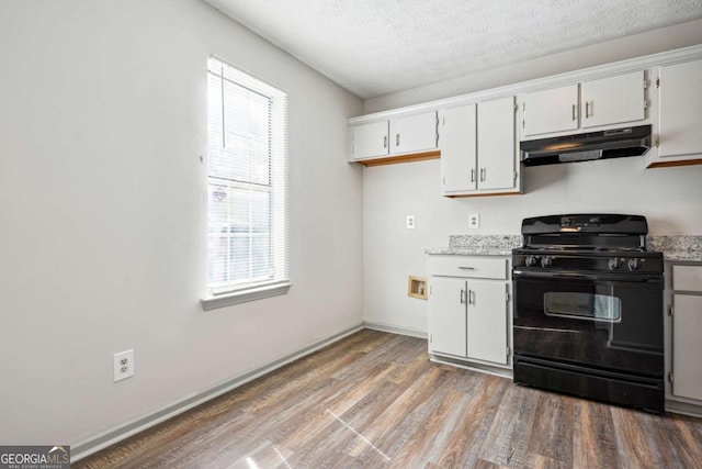 2047 Charter Ln, Lithonia, GA 30058 - kitchen with gas stove, under cabinet range hood, wood finished floors, white cabinets, and a textured ceiling