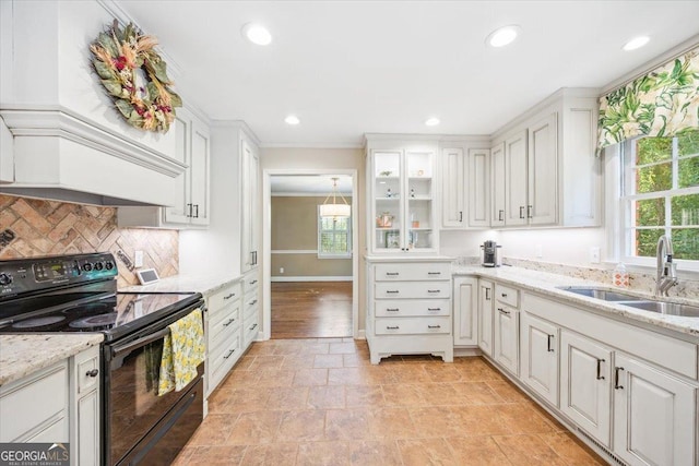 4802 Wesleyan Woods Dr, Macon, GA 31210 - kitchen featuring a healthy amount of sunlight, electric range, a sink, and white cabinetry