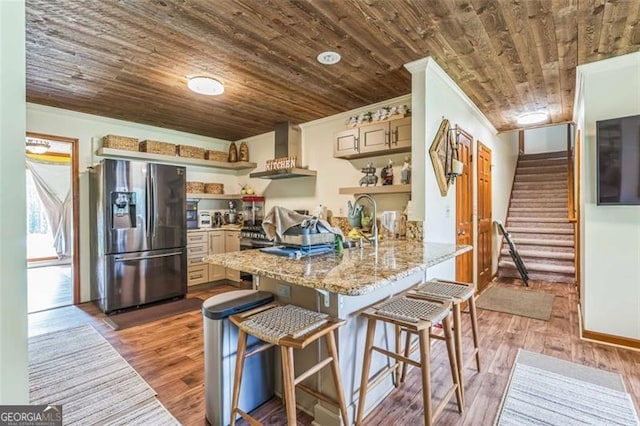 kitchen featuring wall chimney range hood, crown molding, open shelves, stainless steel fridge with ice dispenser, and a peninsula