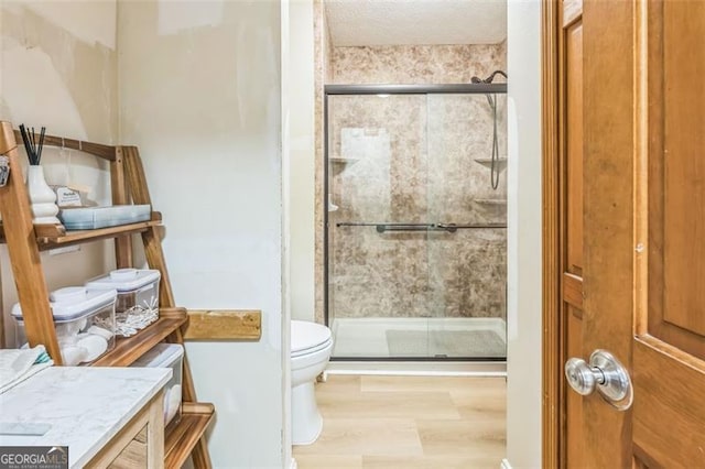 bathroom with toilet, a shower stall, wood finished floors, and vanity