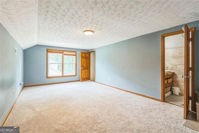 unfurnished bedroom with vaulted ceiling, baseboards, carpet flooring, and a textured ceiling