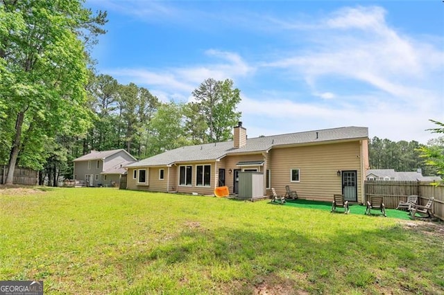 back of property with a yard, fence, and a chimney