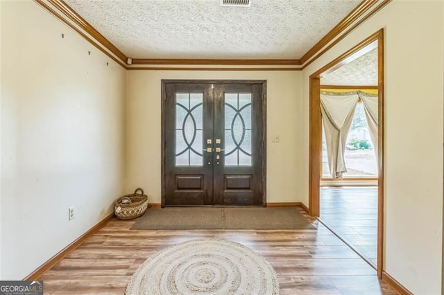 entryway featuring baseboards, ornamental molding, and wood finished floors