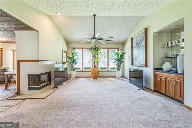 living area featuring ceiling fan, light colored carpet, a tile fireplace, baseboards, and lofted ceiling