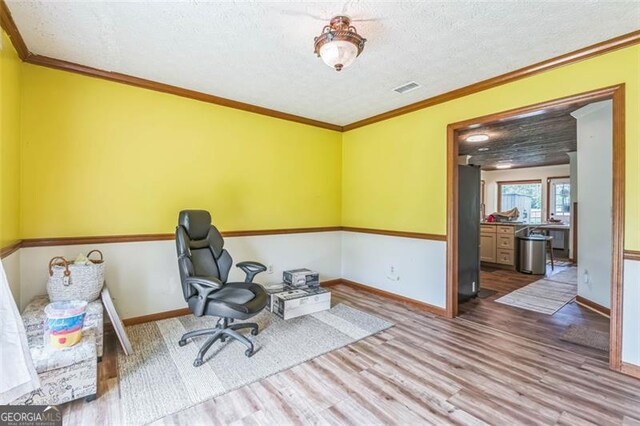 home office with visible vents, ornamental molding, wood finished floors, baseboards, and a textured ceiling