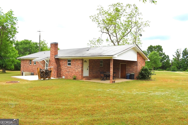 rear view of property featuring a lawn, a patio, and brick siding