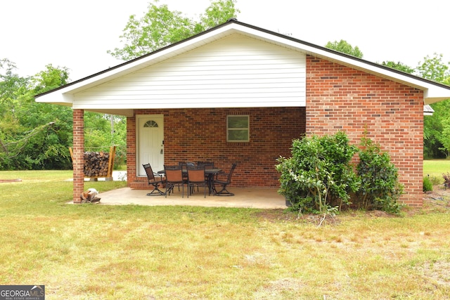 back of house with a patio, a yard, and brick siding