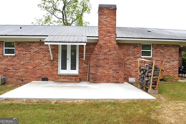 back of property with a patio area, central AC, a chimney, and metal roof