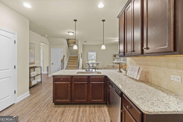 kitchen featuring a peninsula, light wood-type flooring, tasteful backsplash, a sink, and dishwasher