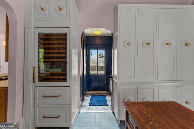 entryway with tile patterned flooring, arched walkways, and wine cooler