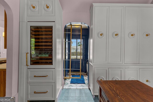 doorway to outside featuring arched walkways, tile patterned floors, and wine cooler