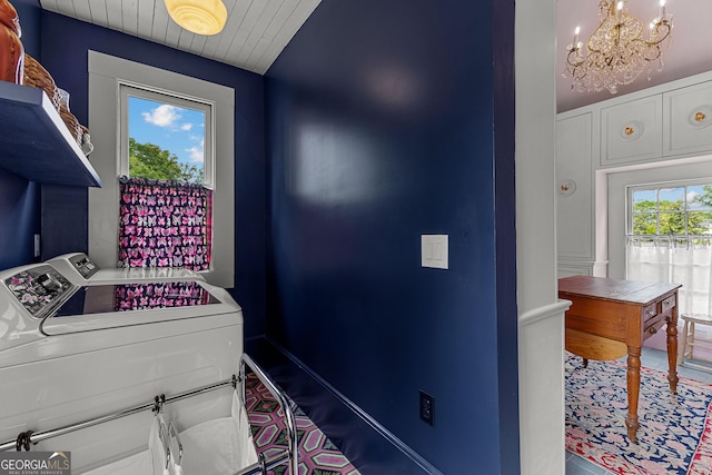 laundry area with laundry area, baseboards, washer and clothes dryer, wood ceiling, and a notable chandelier