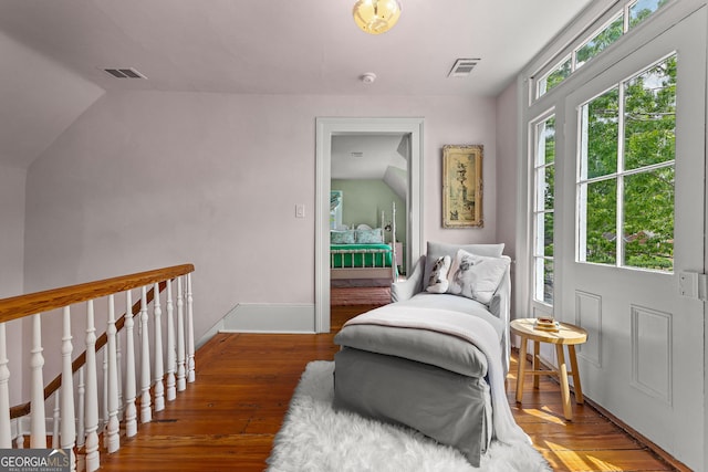 sitting room with baseboards, visible vents, wood finished floors, and lofted ceiling