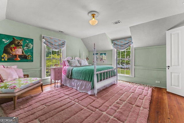 bedroom with multiple windows, wood-type flooring, and lofted ceiling