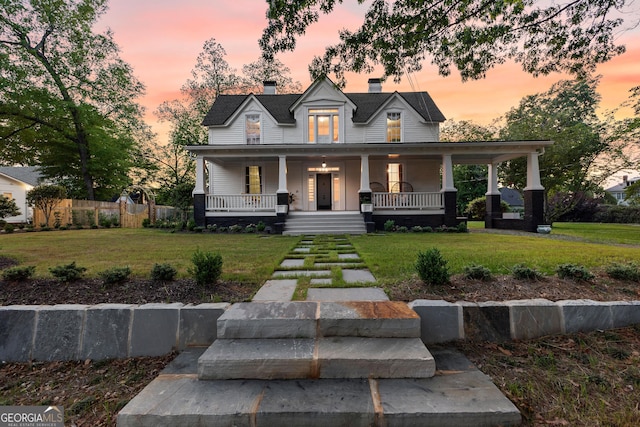 view of front facade with covered porch, a chimney, and a front yard