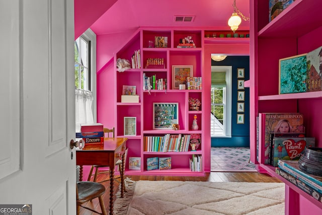 interior space with built in shelves, wood finished floors, and visible vents